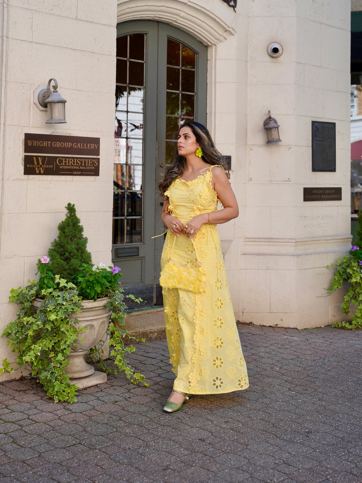 Full-length shot of Roopsi Bansal in the yellow lace dress and green heels outside Wright Group Gallery