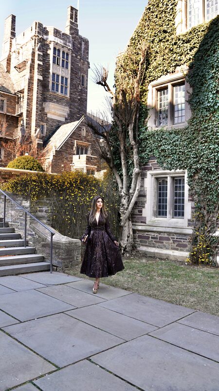Roopsi Bansal in a plum satin midi dress walking past ivy-covered Gothic buildings at Princeton, New Jersey