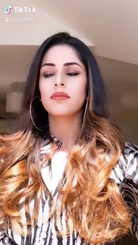 Close-up of Roopsi Bansal with curled hair and hoop earrings, indoors in a black and white printed top
