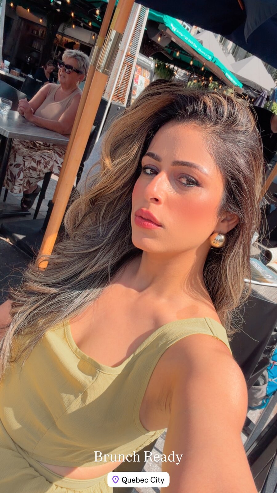 Roopsi Bansal in a yellow tank top on an outdoor cafe patio in Quebec City, captioned Brunch Ready