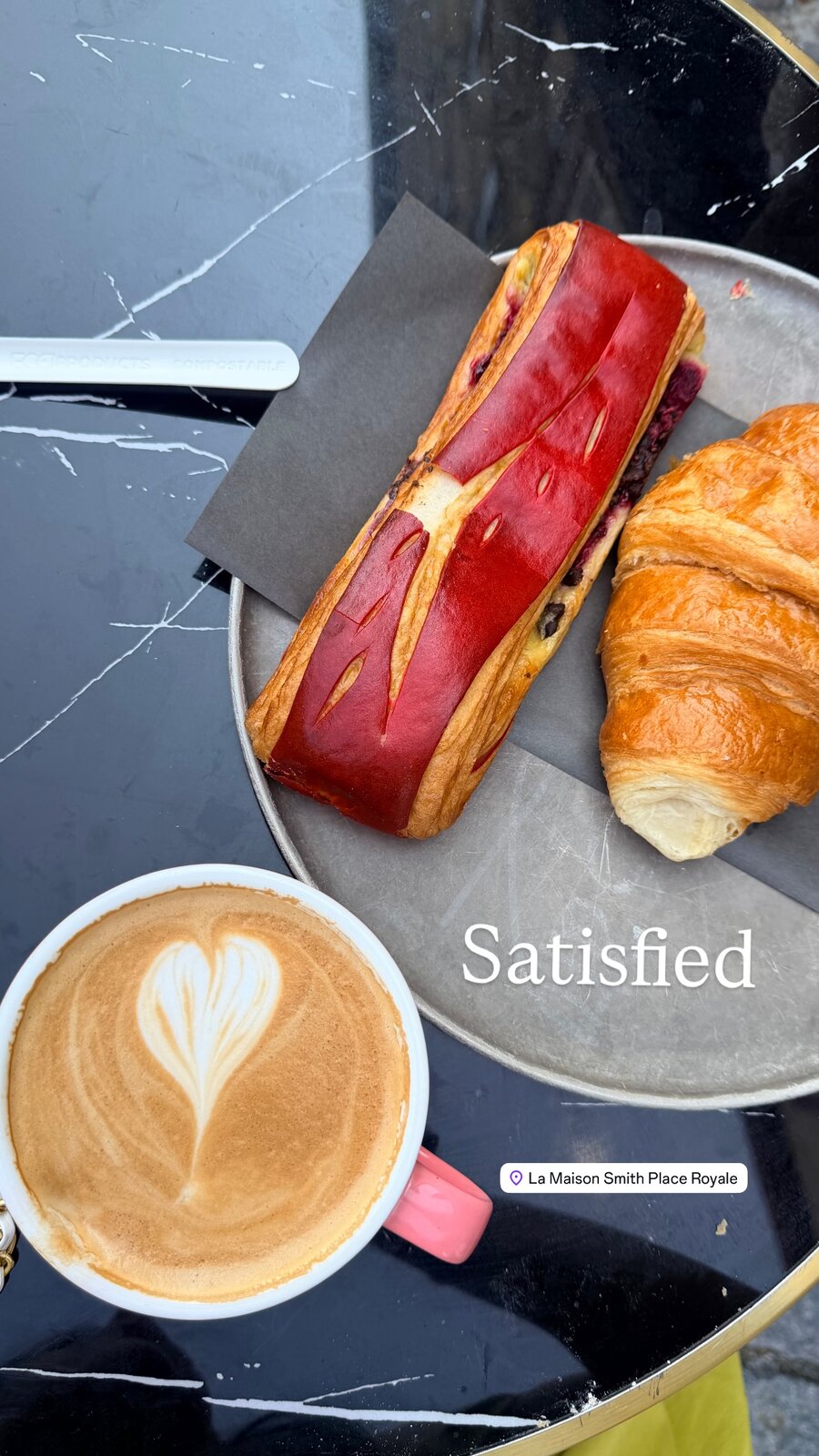 A latte with a heart in the foam next to a berry pastry and croissant on a plate, captioned Satisfied, at La Maison Smith Place Royale in Quebec City