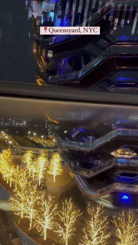 The illuminated Vessel and string-lit trees at Hudson Yards, seen from Queensyard restaurant at night