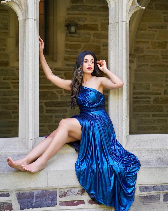 Roopsi Bansal in a metallic blue strapless gown from Mew Mews seated in a Gothic stone archway in Princeton, NJ