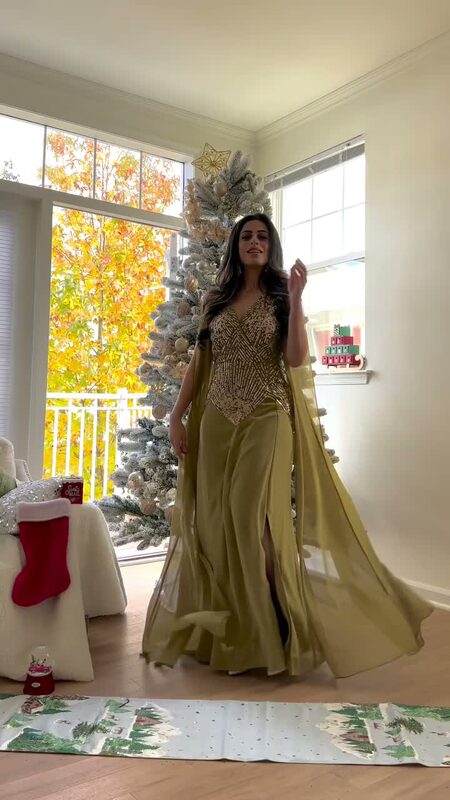 Roopsi Bansal in a gold sequined and chiffon caped gown from Frock and Frill beside a flocked Christmas tree at home