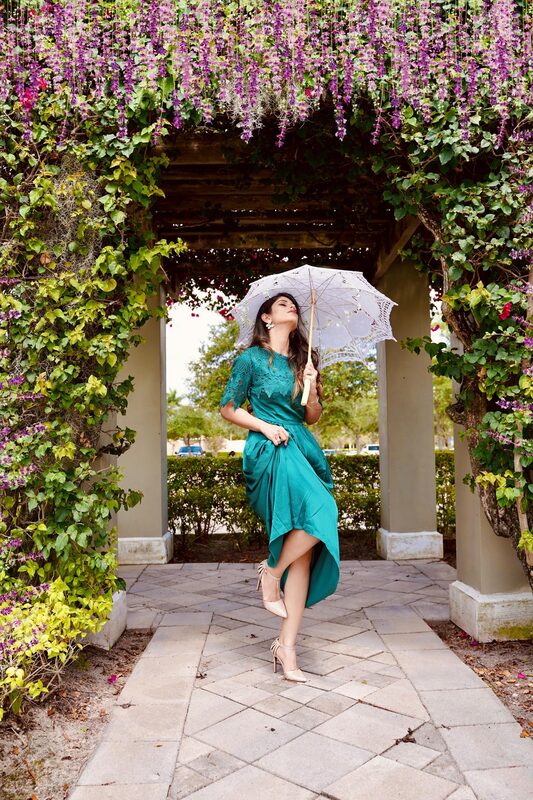 Roopsi Bansal in a plaid off-shoulder crop top and bright yellow maxi skirt from Zara, holding daisies in front of a tiered stone fountain