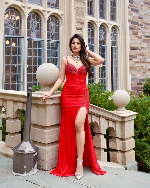 Roopsi Bansal in a red beaded gown from New York Dress with a slit, posed on a stone balcony in Princeton, NJ