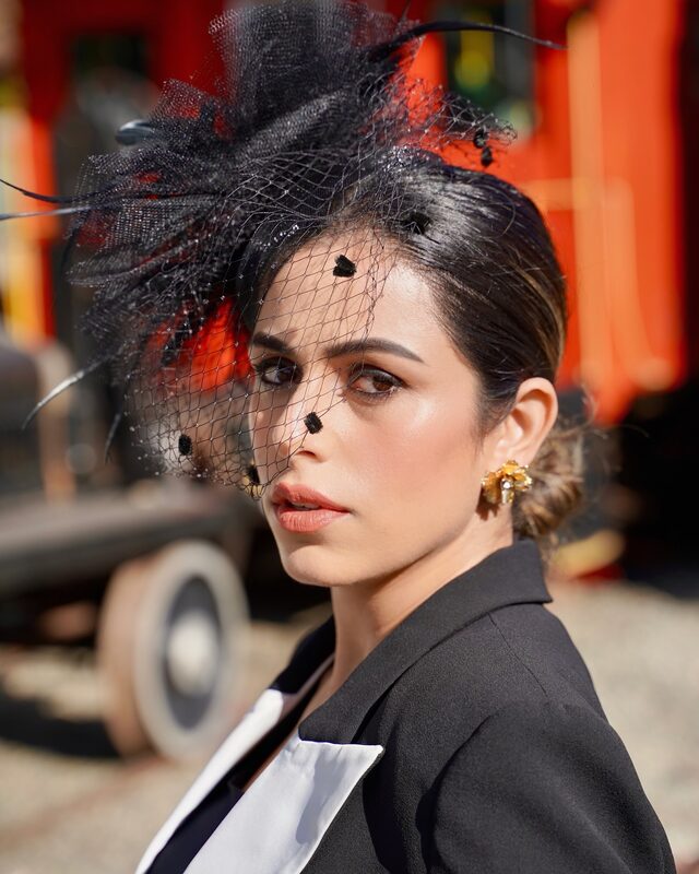 Roopsi Bansal in a retro Halloween suit coat and feather veil headdress from Bella Barnett