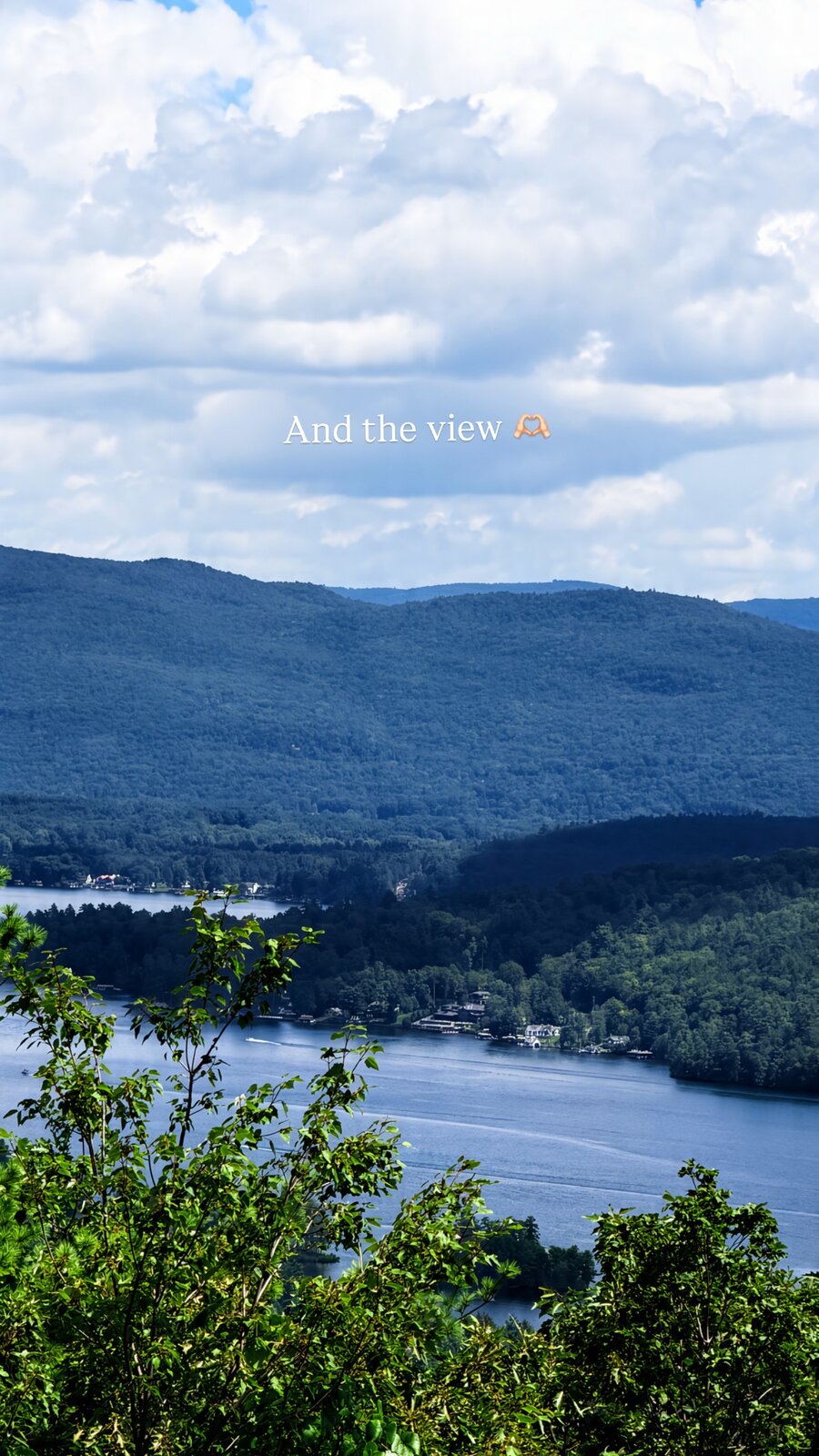 A wide lake surrounded by forested mountains, seen from a scenic overlook in the Adirondacks