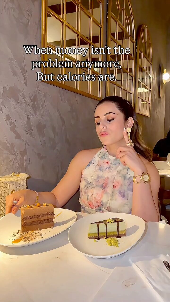 Roopsi Bansal at a restaurant table with two slices of dessert cake, one chocolate and one pistachio