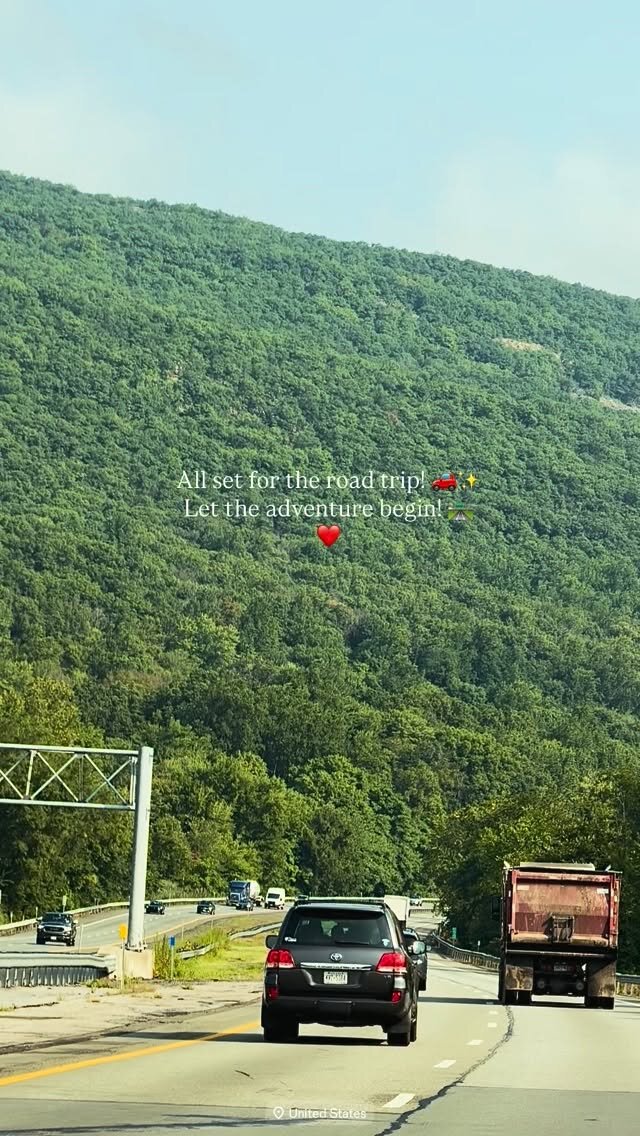 A mountain highway lined with green hills, seen from inside a car setting off on a road trip