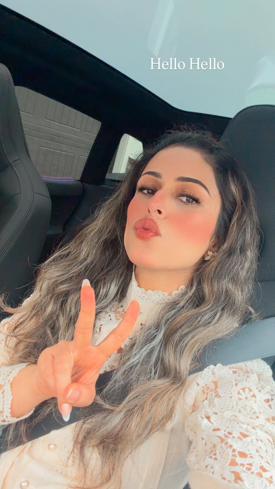 Roopsi Bansal waving hello from the car in a cream lace top