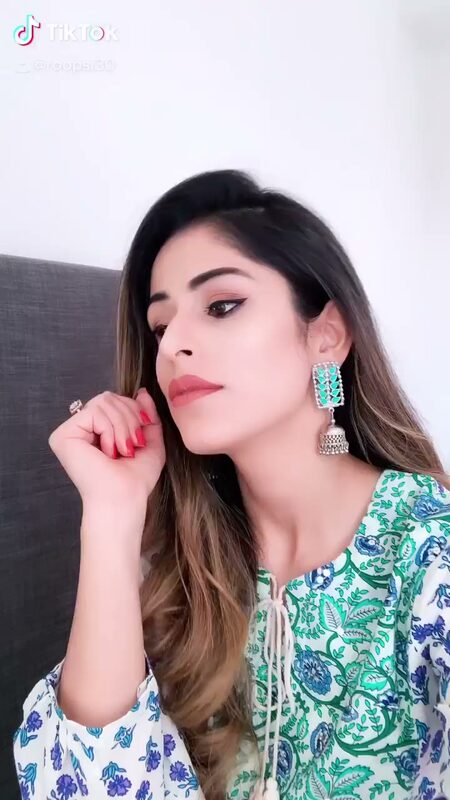 Close-up of Roopsi Bansal in a blue and white floral kurta with statement earrings, resting her chin on her hand