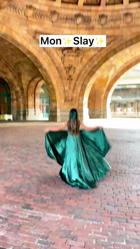 Roopsi Bansal seen from behind, twirling in a flowing emerald green gown beneath a series of stone arches over a brick-paved walkway
