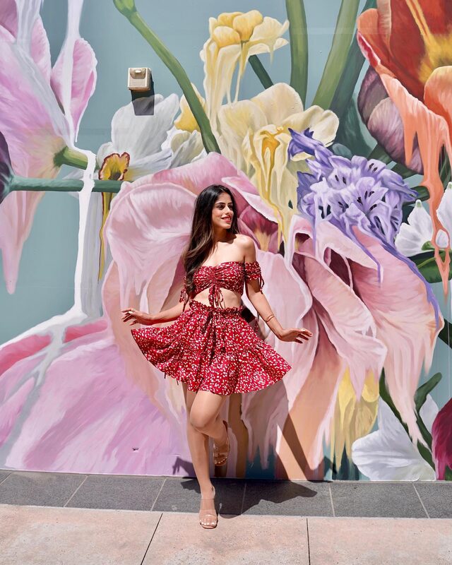 Roopsi Bansal in a red floral off-shoulder crop top and matching flared mini skirt from Romwe, standing in front of a large floral mural in Buckhead, Georgia