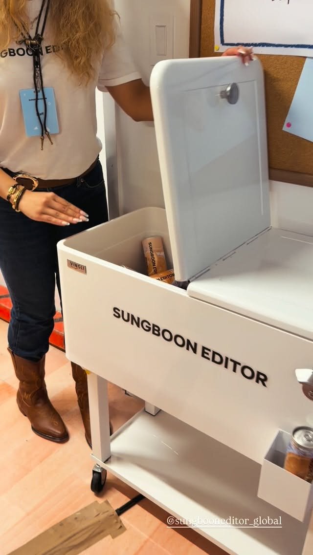 A Sungboon Editor staff member in cowboy boots opening a branded cooler cart at the popup