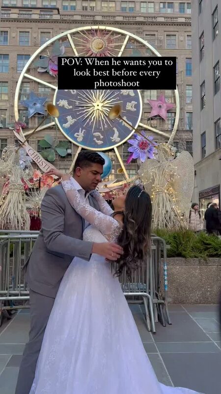 Roopsi Bansal in a white lace gown and her husband in a grey suit embracing near a decorated Christmas installation at Lotte New York Palace