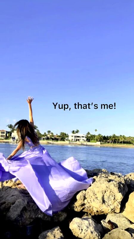 Roopsi Bansal in a flowing lavender gown from Miss Juana, one arm raised, seated on rocks at the water's edge at Dubois Park, with the text overlay 'Yup, that's me!'