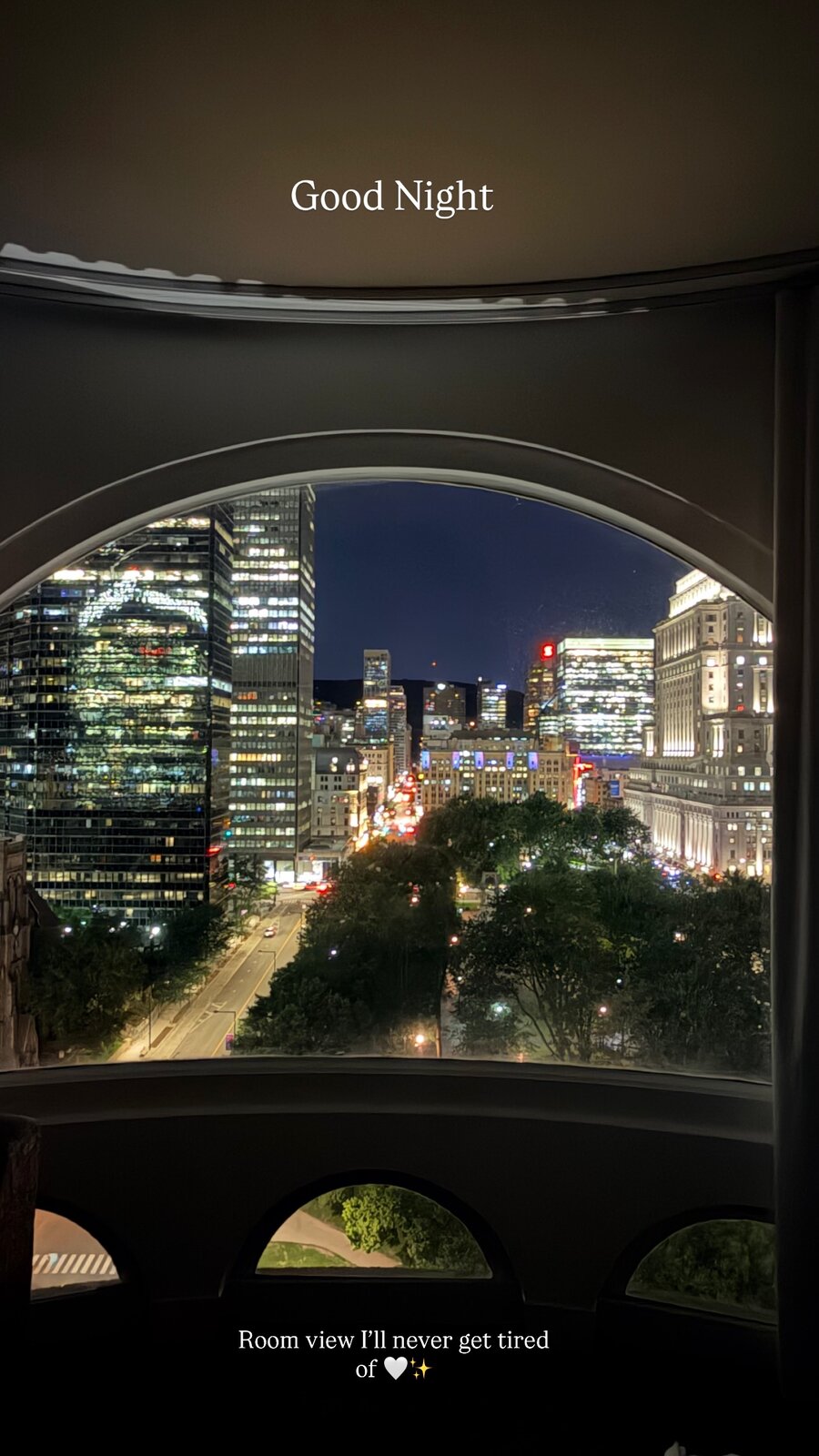 The Montreal downtown skyline lit up at night, seen through the same large arched hotel window, captioned Good Night
