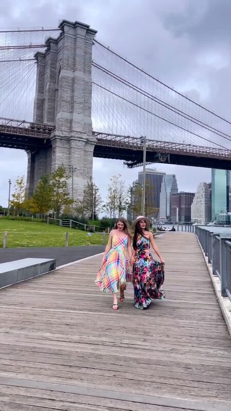 Roopsi Bansal and a friend in colorful printed dresses walking under the Brooklyn Bridge in DUMBO