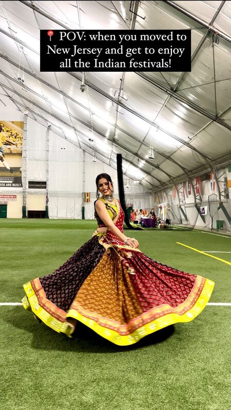 Roopsi Bansal twirling in a maroon, mustard, and black lehenga on an indoor turf field at a festival celebration in New Jersey