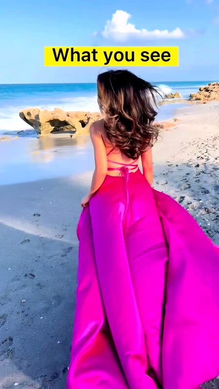 Roopsi Bansal from behind in a magenta backless gown, walking along a rocky Florida beach, with on-screen text reading What You See