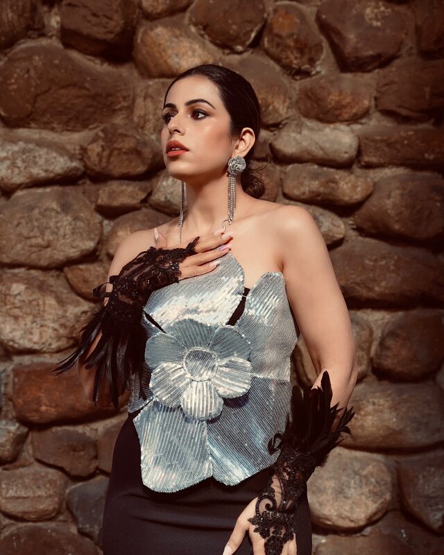 Roopsi Bansal in a black sequin Halloween dress with feather hand ornament from Bella Barnett