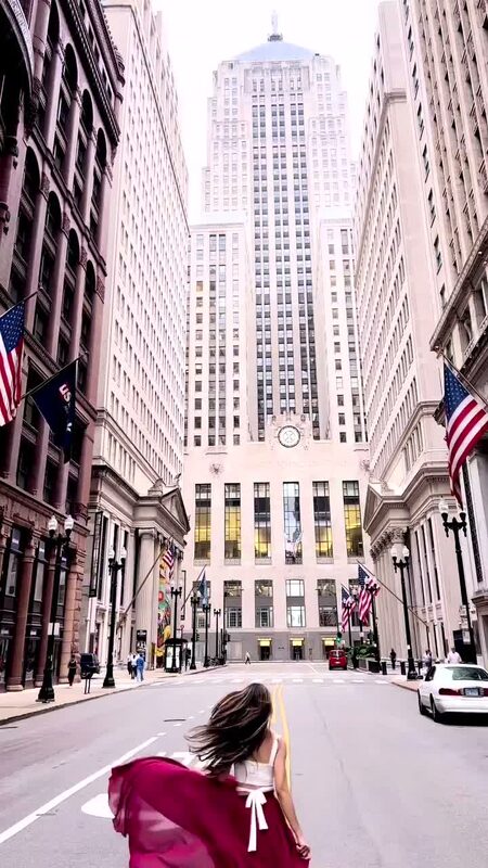 Roopsi Bansal from behind in a magenta dress, twirling in the middle of LaSalle Street in Chicago with the Board of Trade Building ahead