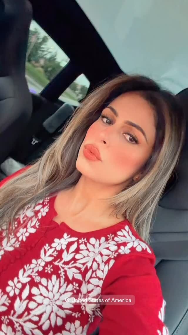 Roopsi Bansal taking a car selfie in a red long-sleeve top with a white floral embroidered pattern